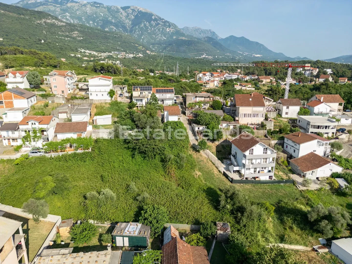Pogled iz vazduha na okolno naselje i planine u pozadini.