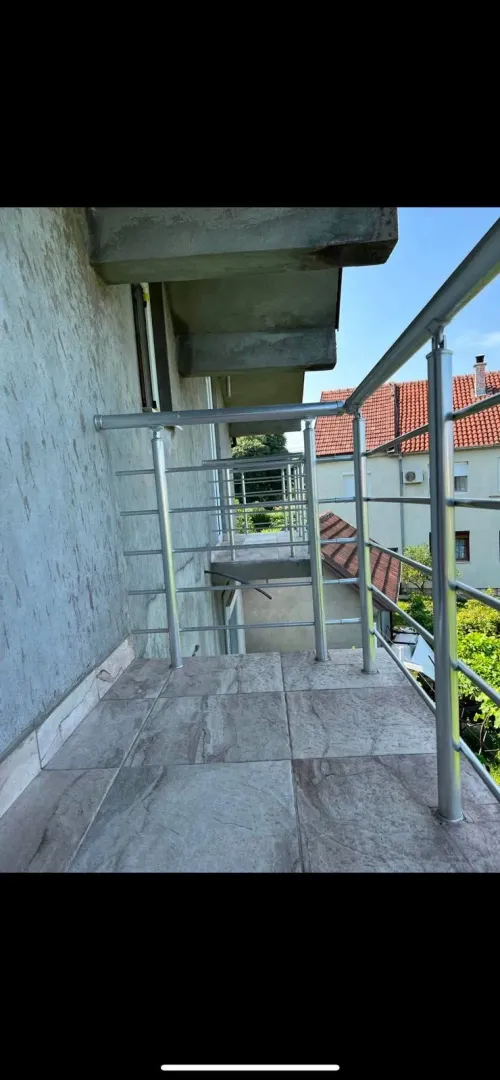 View of a tiled balcony with a metal railing and surrounding houses.