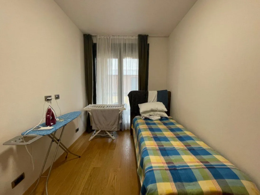 A small bedroom with a single bed and an ironing board.