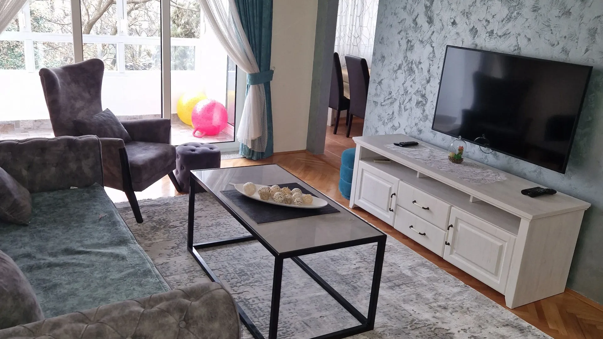 Moderan dnevni boravak sa garniturom, TV komodom i izlazom na terasu.