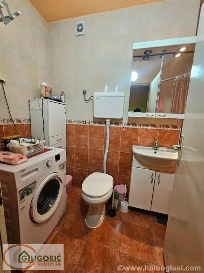 Small bathroom with washing machine, toilet, and vanity unit with sink.