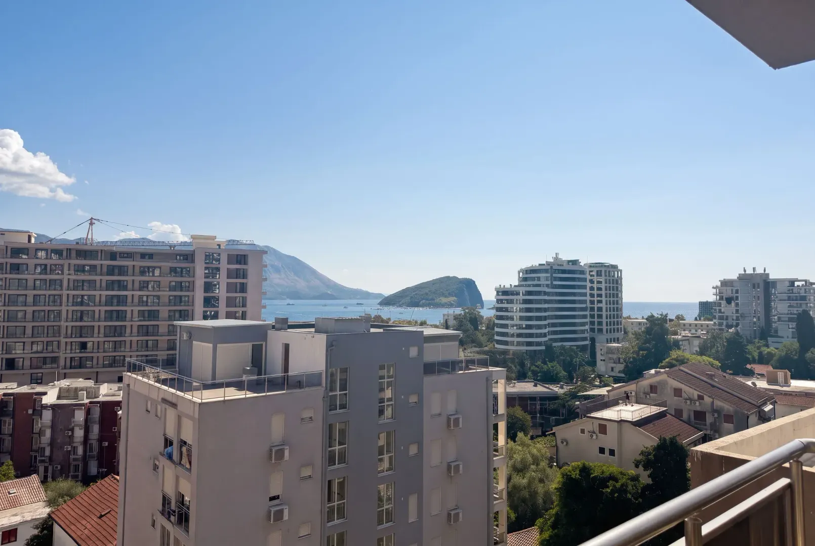 Pogled na grad, okolne zgrade i more sa terase nekretnine.