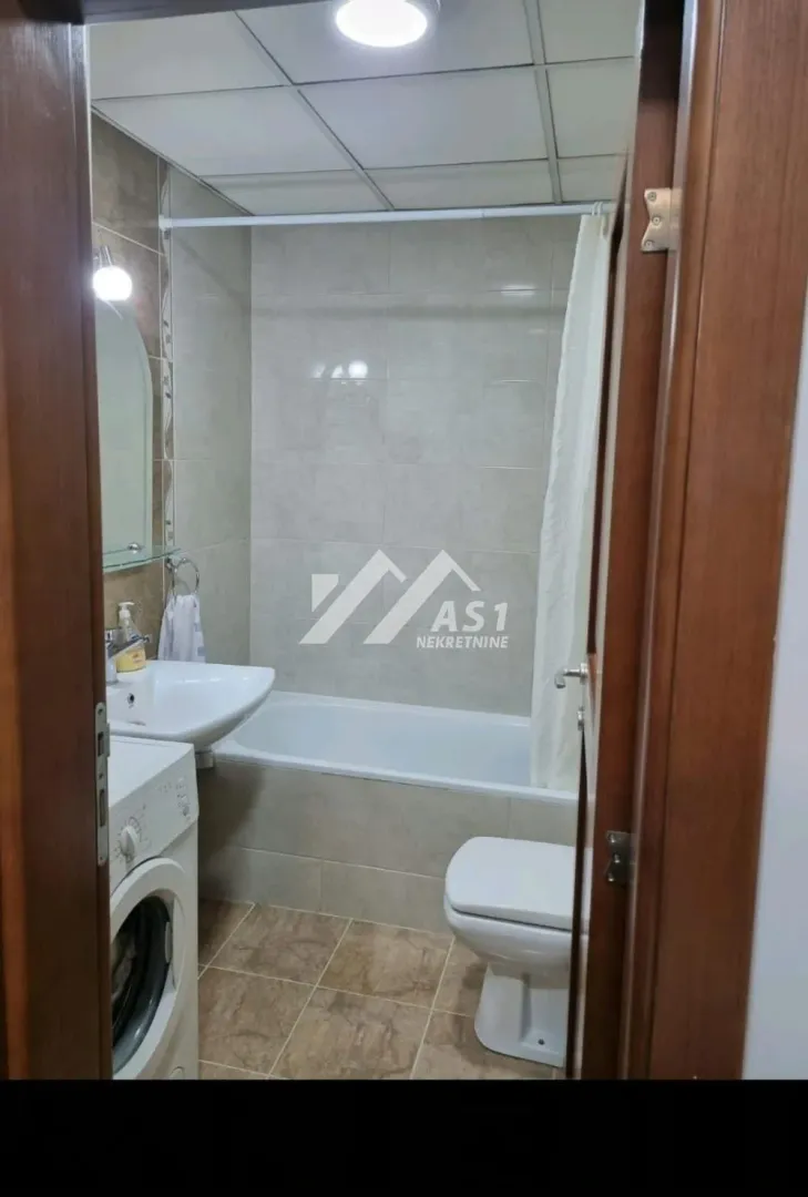View from the doorway into the bathroom featuring a bathtub, sink, toilet, and washing machine.