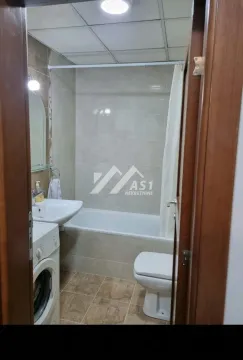 View from the doorway into the bathroom featuring a bathtub, sink, toilet, and washing machine. - image 3