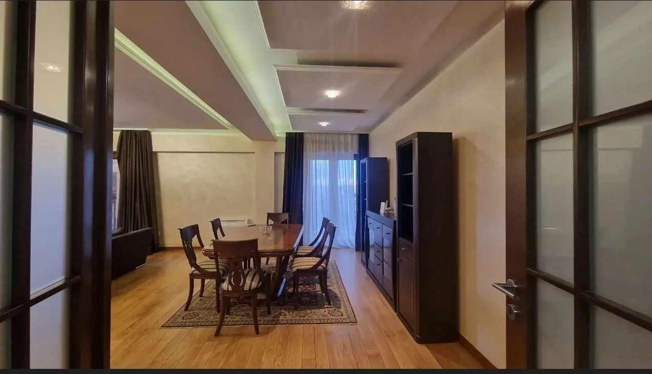 A spacious dining area with a wooden table and chairs, connected to the living room.
