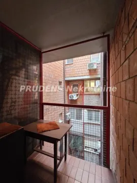 Manji zatvoreni balkon sa stolom i pogledom na susednu zgradu. - image 5
