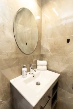 Modern bathroom with a sink, mirror, and beige tiles. - image 4