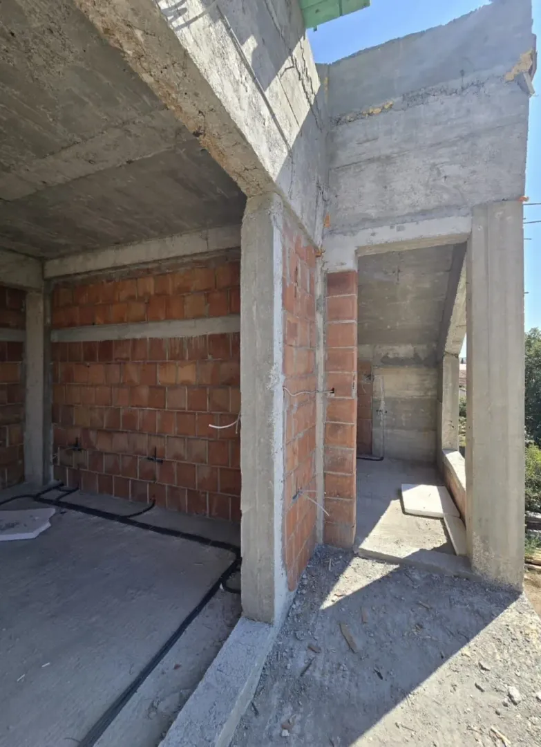 Unutrašnjost objekta u izgradnji sa betonskim stubovima i ciglama.