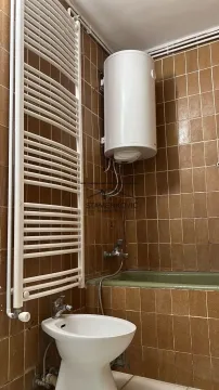 Bathroom with brown tiles, water heater, bathtub, and bidet. - image 4