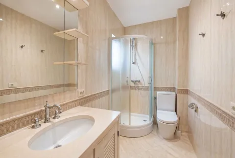 Furnished bathroom with a sink, shower cabin, and toilet in beige tones. - image 8