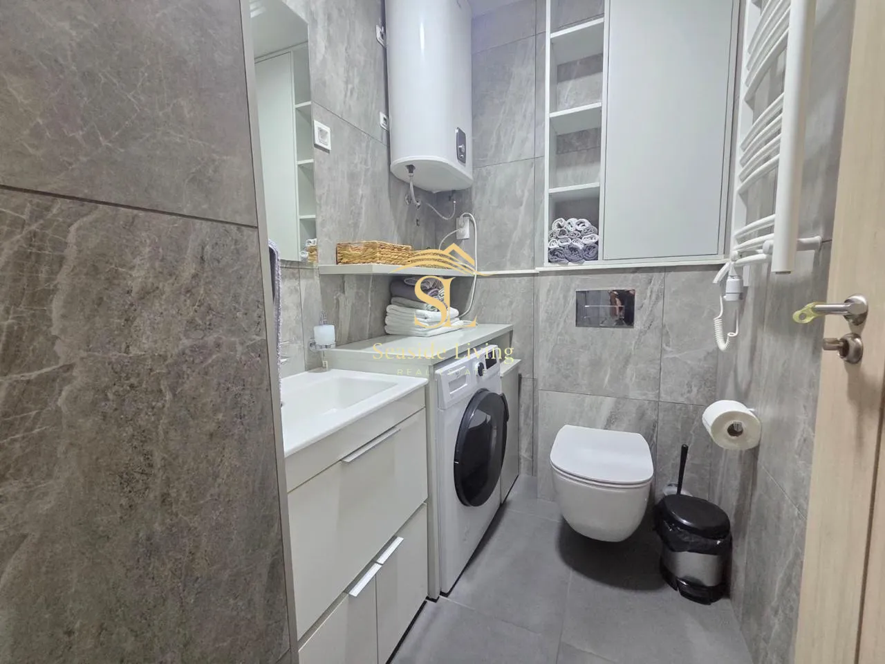 Modernly equipped bathroom with a shower, sink, and washing machine.