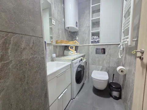 Modernly equipped bathroom with a shower, sink, and washing machine. - image 11