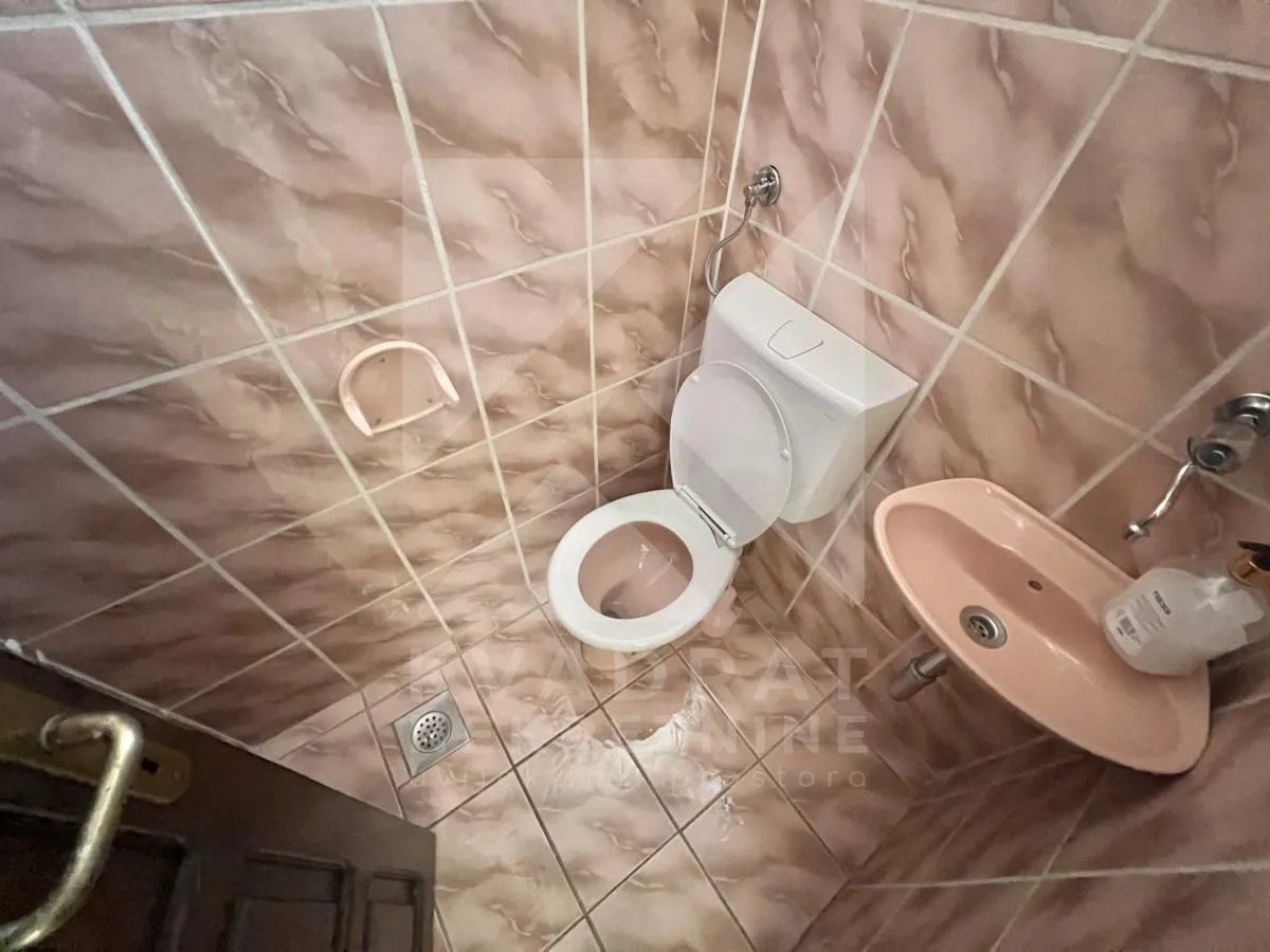 Small tiled bathroom with a toilet and a sink.