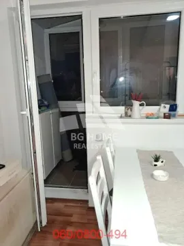 Pogled iz enterijera na zatvorenu terasu sa belim trpezarijskim stolom u prvom planu. - image 16