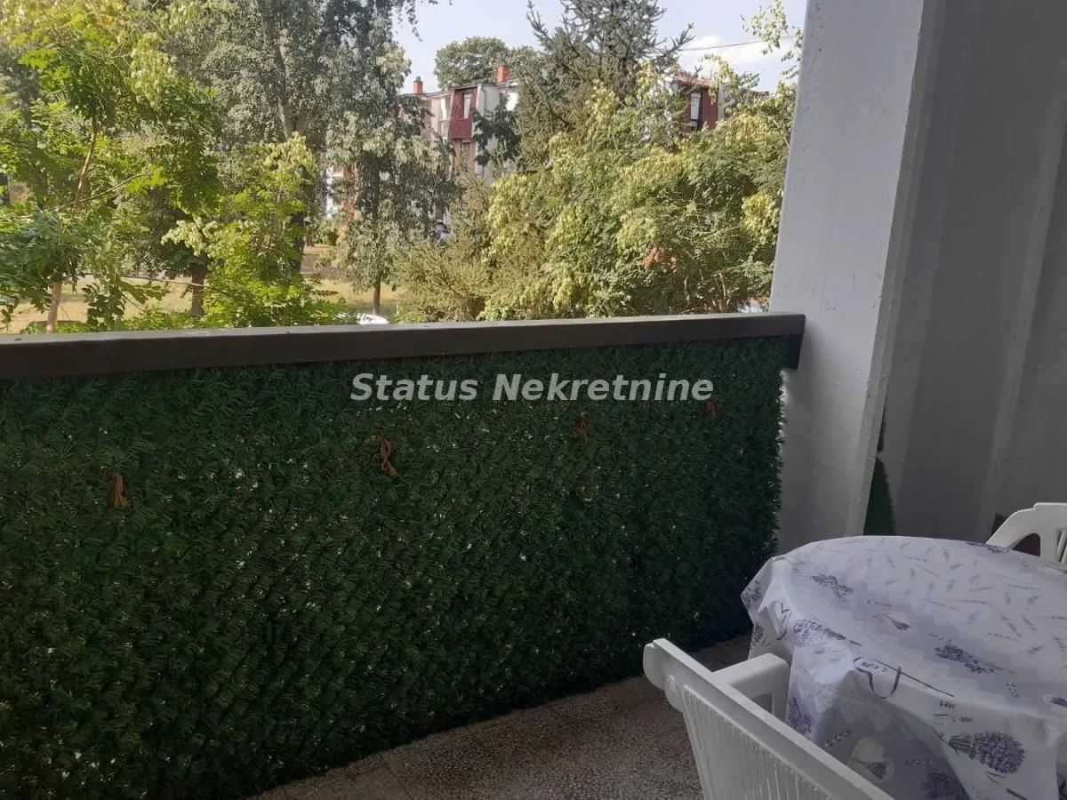 Manji namešteni balkon sa pogledom na zelenilo i drveće.