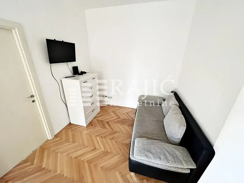 Living room with a sofa, chest of drawers, and television.
