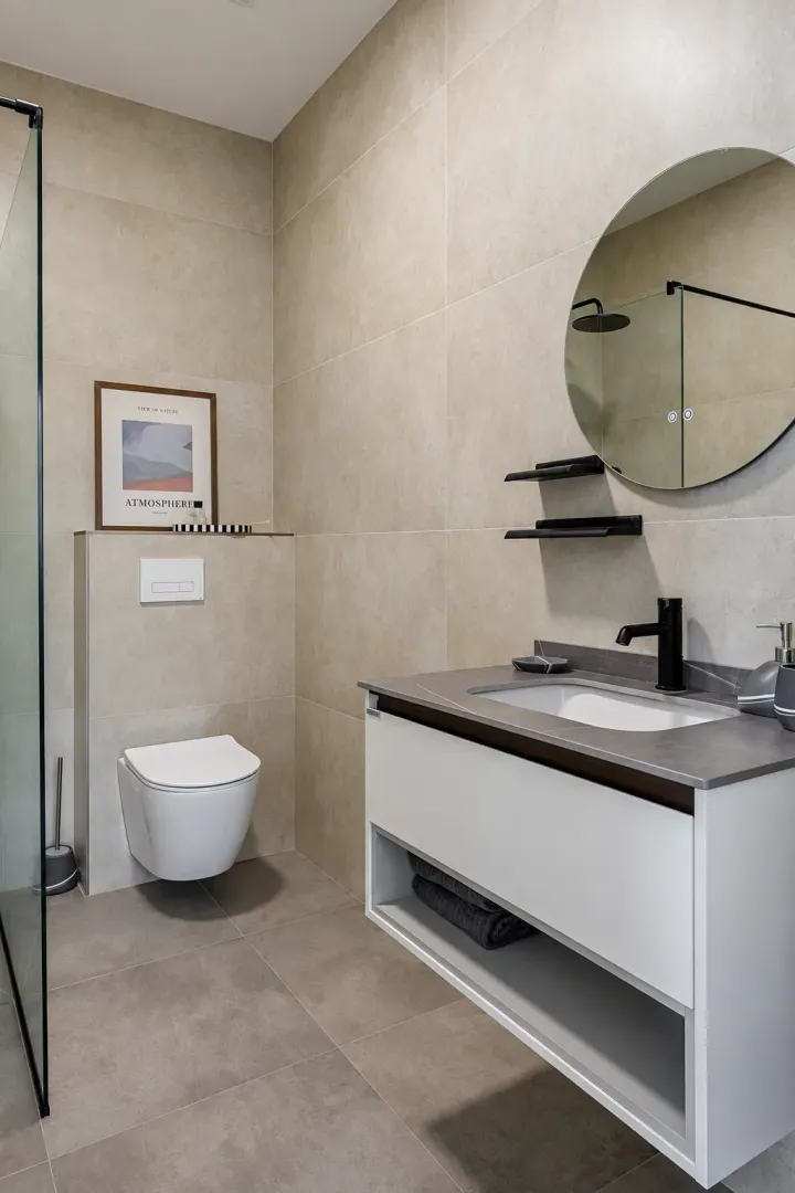 Modern bathroom with a walk-in shower, washbasin, and wall-mounted toilet.