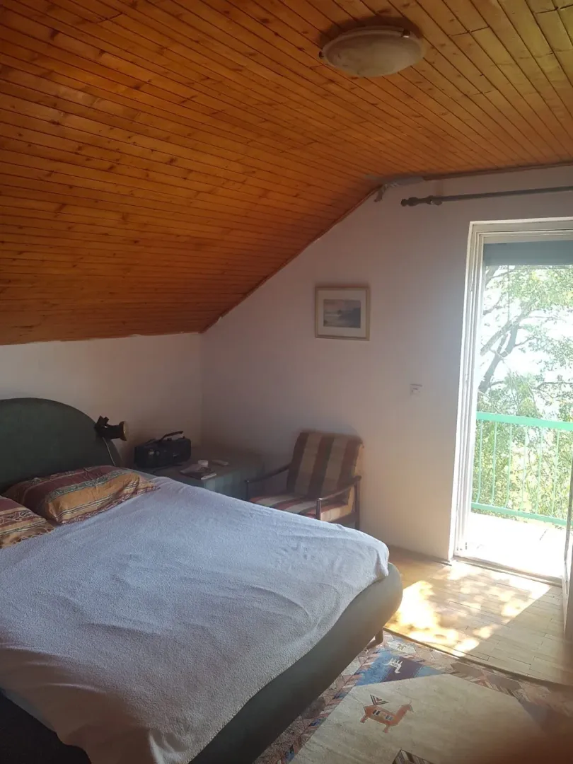 Bedroom with a double bed, wooden ceiling, and balcony access.