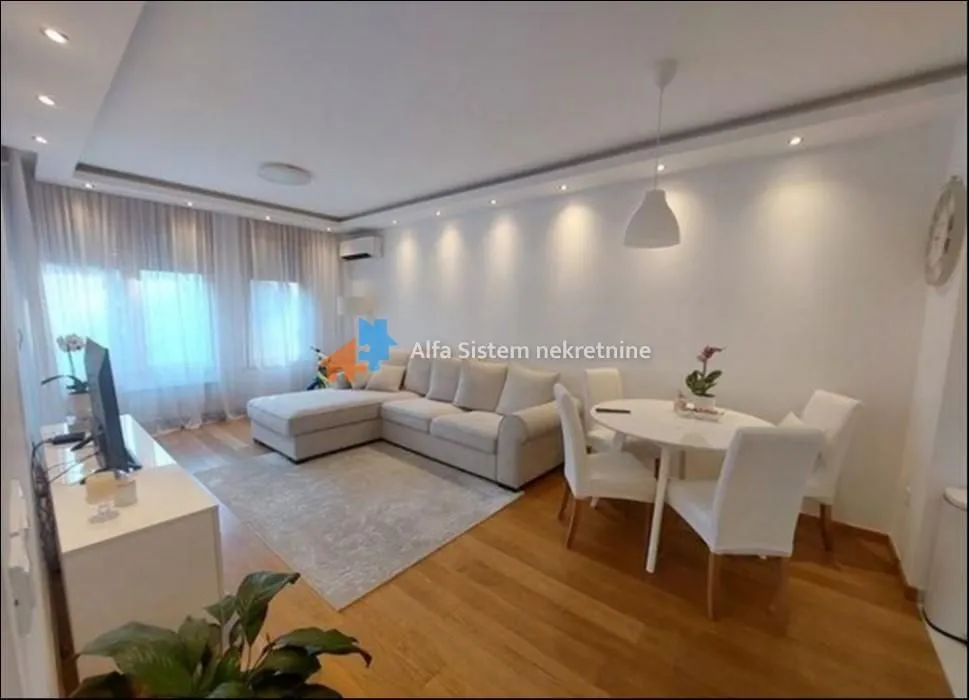 Living room with sofa, dining table and hardwood flooring.