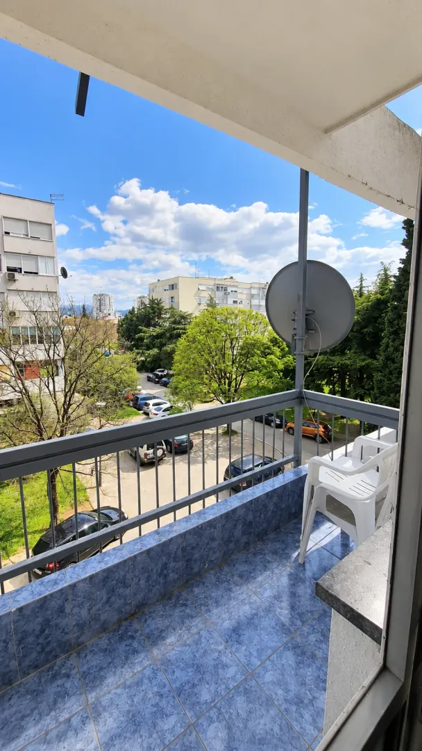 Manji popločani balkon sa pogledom na grad i zelene površine.