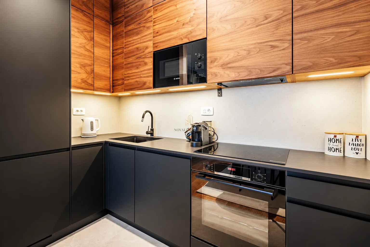 Modern kitchen with wooden cabinetry, black countertops and built-in appliances.