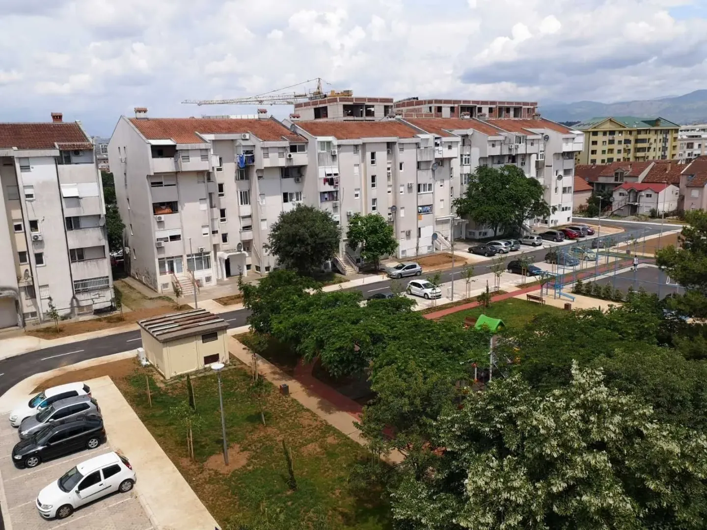 Pogled sa visine na stambene zgrade i dvorište sa zelenilom.