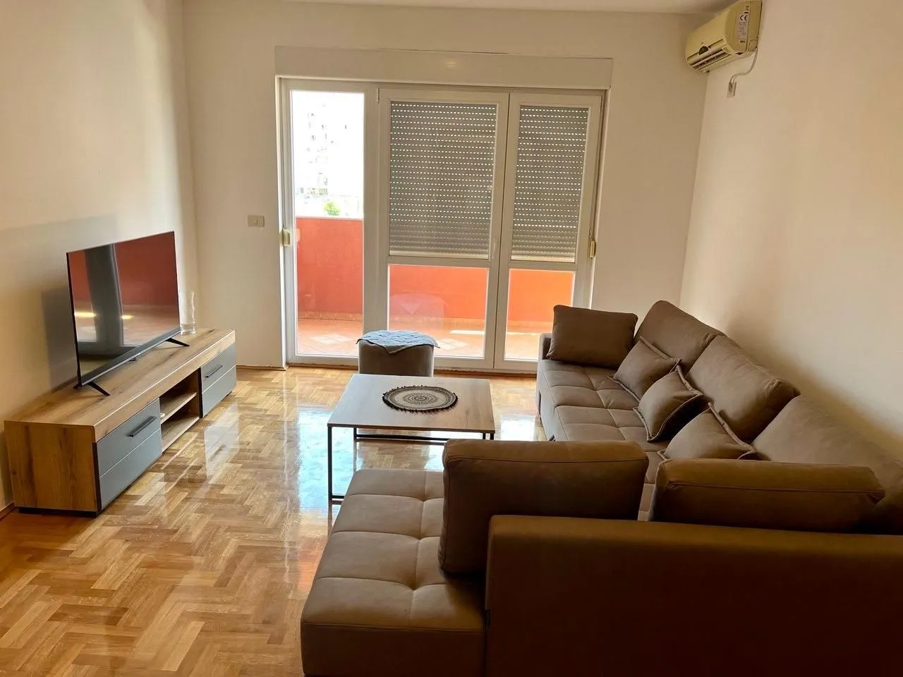 Furnished living room with a sofa set, TV unit, and access to the terrace.