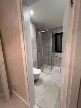 Pogled iz hodnika na moderno uređeno kupatilo sa tuš kabinom. - image 11