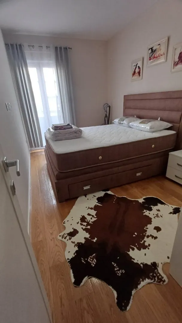 Bedroom with a double bed, wooden flooring, and balcony doors.