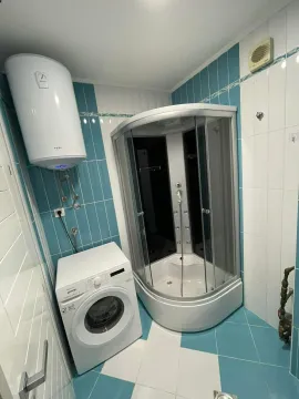Bathroom with a shower cabin, water heater, and washing machine. - image 4