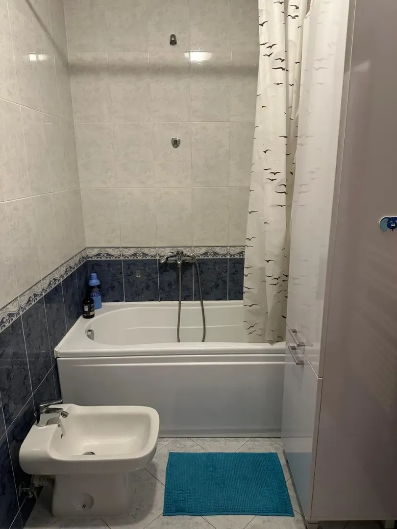 Smaller bathroom with a bathtub, bidet, and white cabinetry.