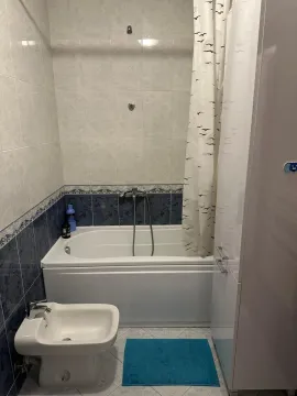 Smaller bathroom with a bathtub, bidet, and white cabinetry. - image 12