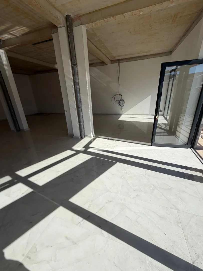 Unfinished commercial space with tiled floor and glass door.