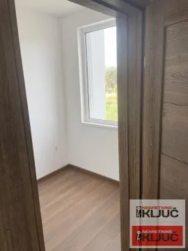 Pogled kroz vrata na praznu sobu sa laminatom i prozorom. - image 4