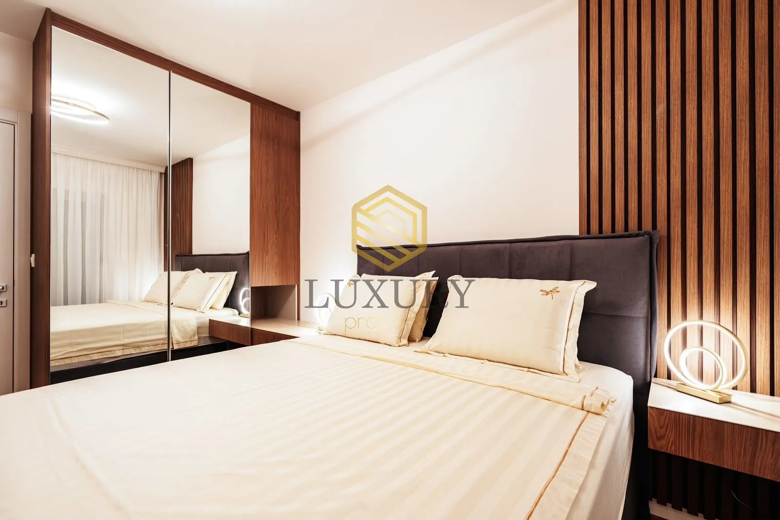 Modern bedroom with a double bed, wooden wall panels, and a large mirror.