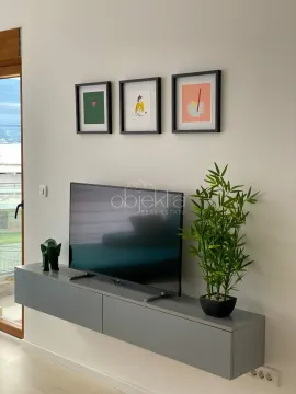 Detalj enterijera sa televizorom, komodom i slikama na zidu. - image 4