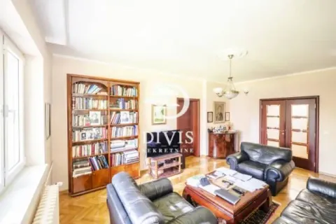 Spacious living room with seating furniture, large bookcase and hardwood floor. - image 15