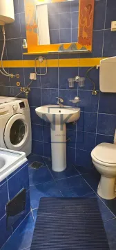 Kupatilo sa plavim pločicama, umivaonikom, WC šoljom i veš mašinom. - image 6