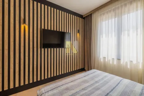 Spavaća soba sa bračnim krevetom, TV-om na zidu sa drvenim letvicama i prozorom sa zavesama. - image 7