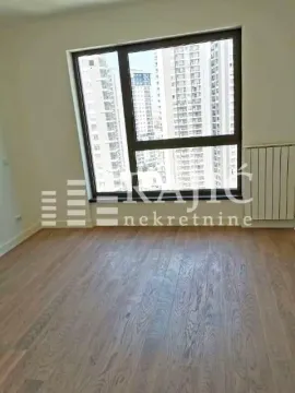 Empty room with hardwood floors and a large window with a view of buildings. - image 3