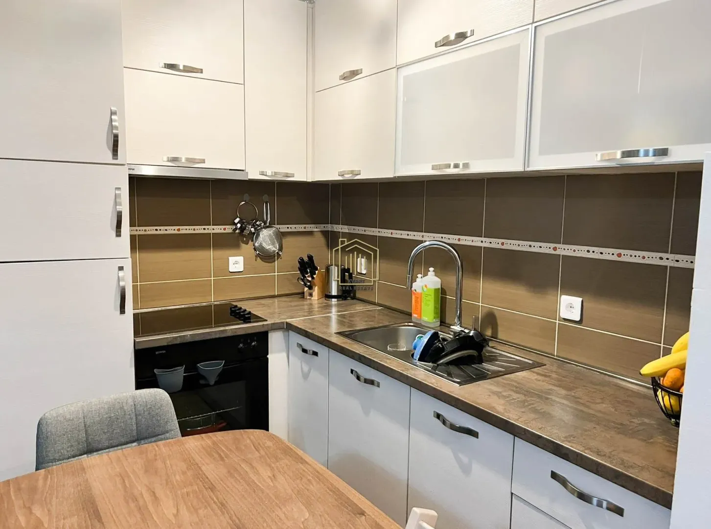 Kitchen with white cabinetry, sink, and built-in oven.