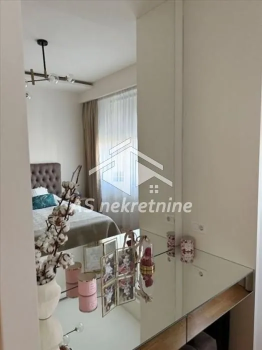 Pogled iz hodnika na spavaću sobu sa krevetom i ogledalom.