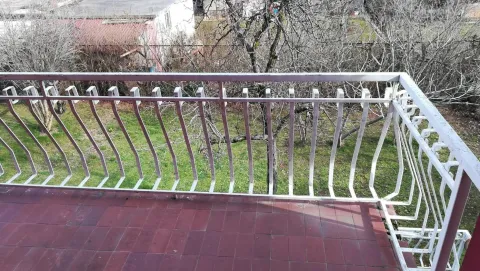 Pogled sa balkona na popločanu terasu i dvorište sa drvećem. - image 8