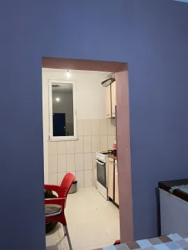 Pogled kroz prolaz na jednostavnu kuhinju sa šporetom i bijelim pločicama. - image 12