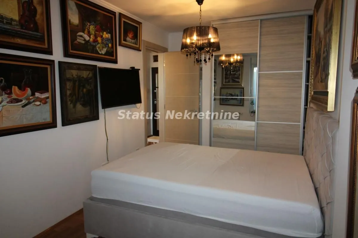 Furnished bedroom with a double bed, wardrobe, and paintings on the wall.