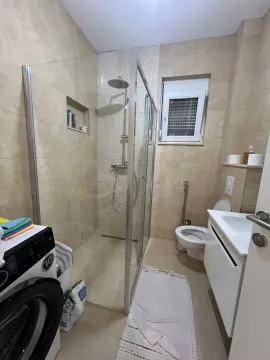 Modern bathroom equipped with a walk-in shower, washbasin, and washing machine. - image 5