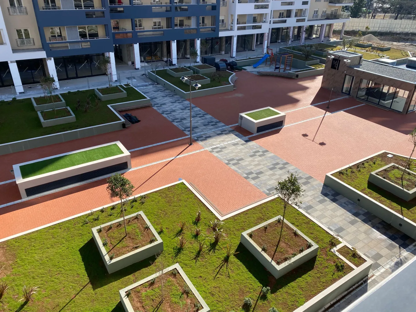 High-angle view of the landscaped courtyard and square in front of the residential building.