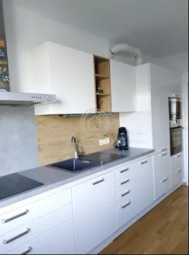 Moderna bela kuhinja sa sudoperom, ugradnim aparatima i drvenim detaljima. - image 3