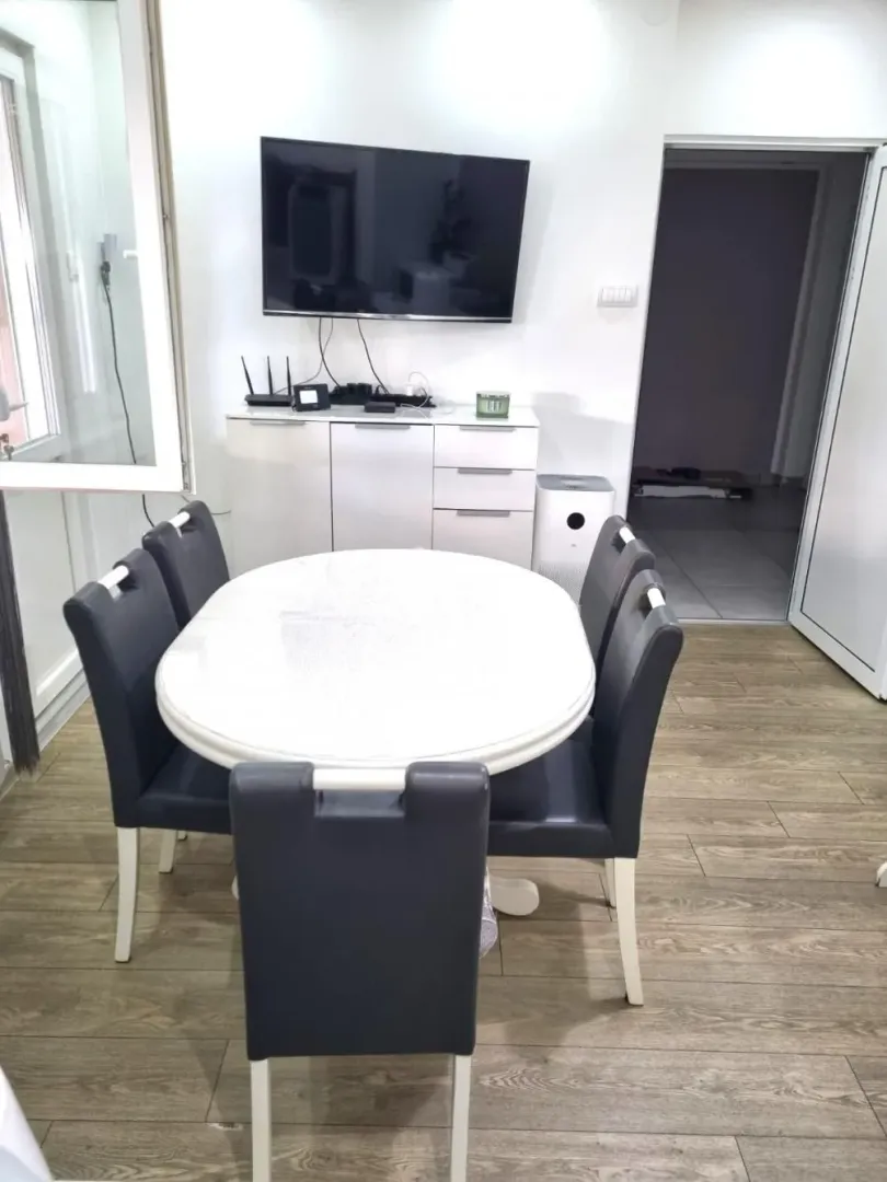 Dining area with a table, chairs, and a wall-mounted TV.