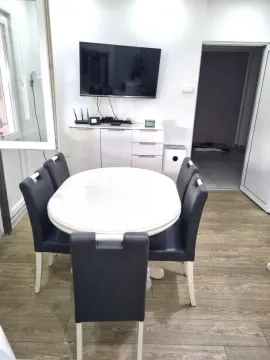 Dining area with a table, chairs, and a wall-mounted TV. - image 5